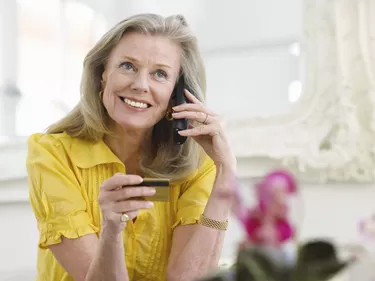 Mature Woman Using Credit Card And Phone