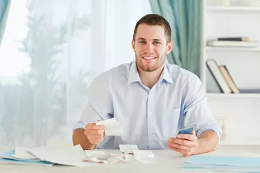 Businessman with pocket calculator checking bills