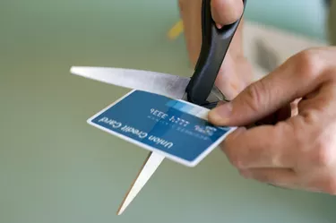Hands cutting credit card with scissors