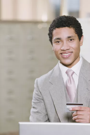 Mixed race businessman with laptop holding credit card