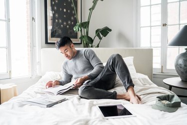 Man in comfortable clothes reading on a bed