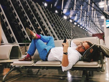Man lying on seats at airport gate