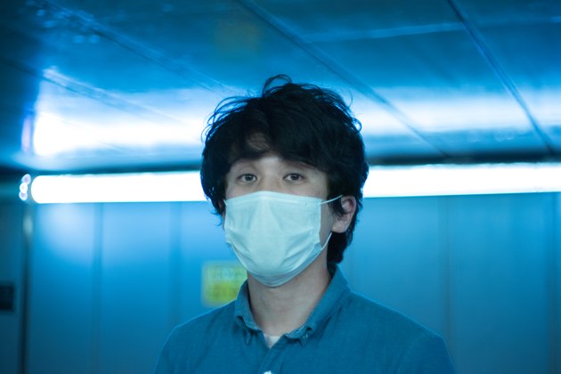 A man in a surgical mask and the city at night