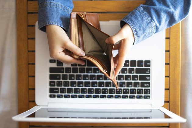 Unemployed looking at his empty wallet. Concept of online job.