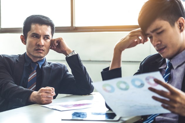 Unhappy business manager and young businessman partner in meeting room at the office. They are under stress because of bad financial document report. Company crisis concept.