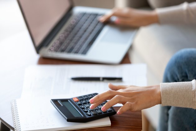 Businesswoman using calculator and laptop for budget cost management, closeup