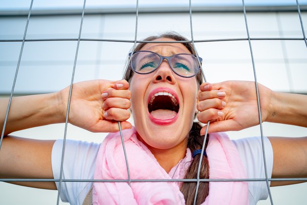 Young Woman Screaming Through Fence Due To Restraining Order