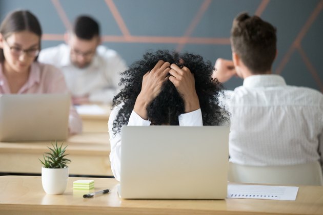 Frustrated african-american woman feeling despair in shared office with laptop