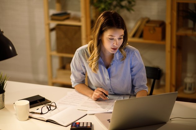 Young woman doing finances at home using laptop
