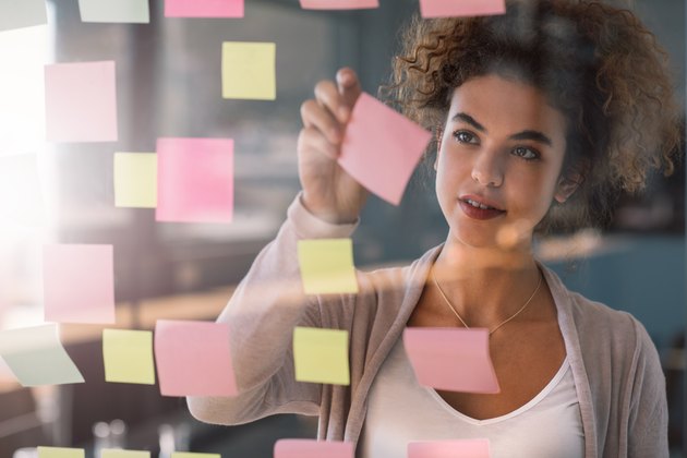 Young businesswoman brainstorming with adhesive notes on a glass wall