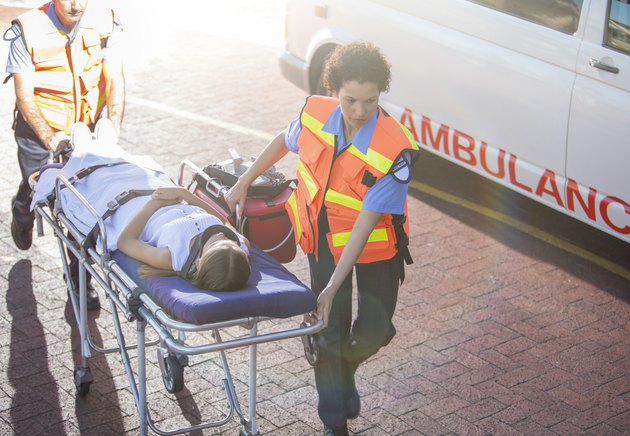 Paramedics wheeling patient in hospital parking lot