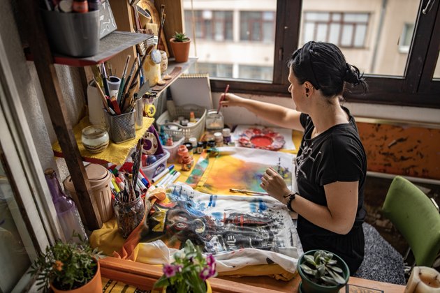 Mid adult new wave artist observing her art and deciding is any change is needed