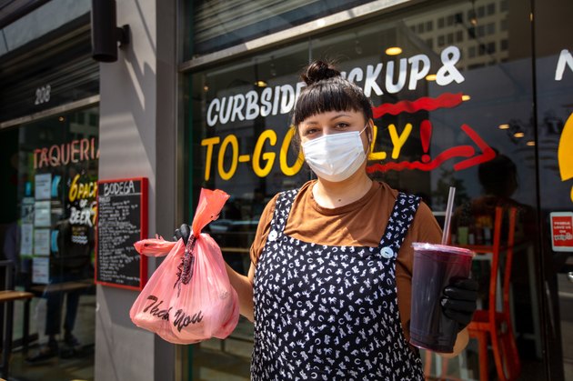 Portrait of Restaurant Proprietor Holding Takeout Order Outside Restaurant During Covid-19 Lockdown