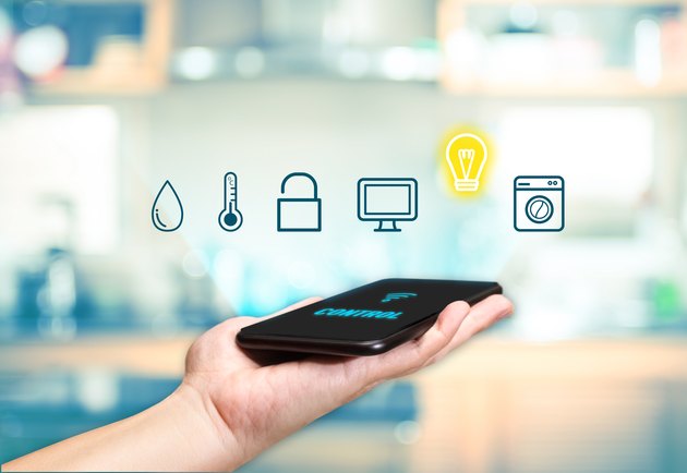 Hand holding mobile with Smart home control icon feature with blur kitchen background,Digital Lifestyle concept