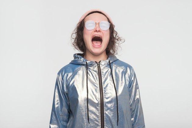 Emotional angry woman in silver coat and sunglasses screaming