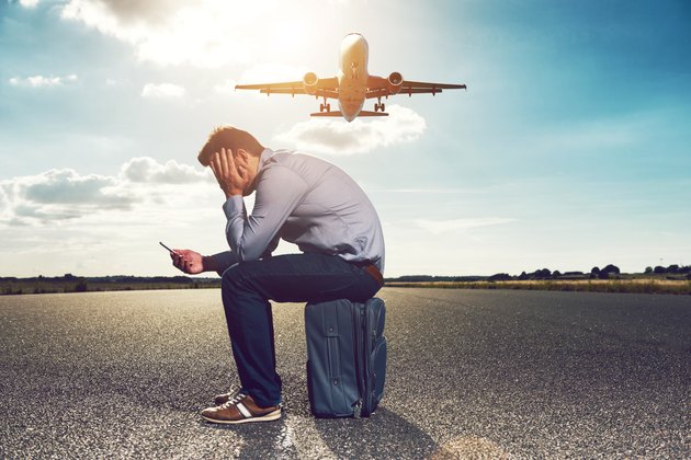 Frustrated passenger waits for plane while looking at phone