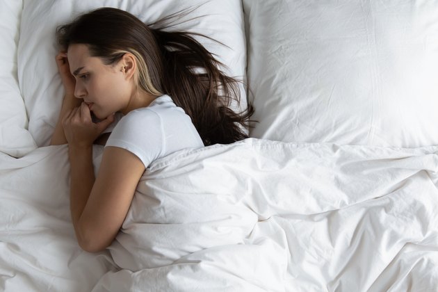 Anxious young woman relaxing in bed feeling lonely