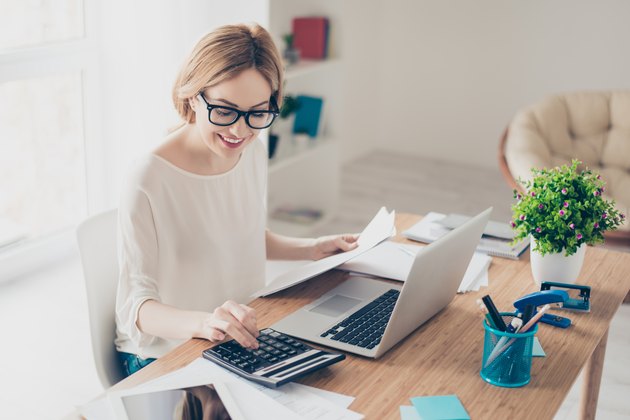 Happy cute pretty accountant working with computer and calculator