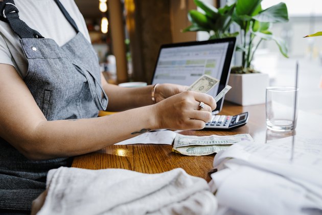 Waitress counting tips at counter in restaurant