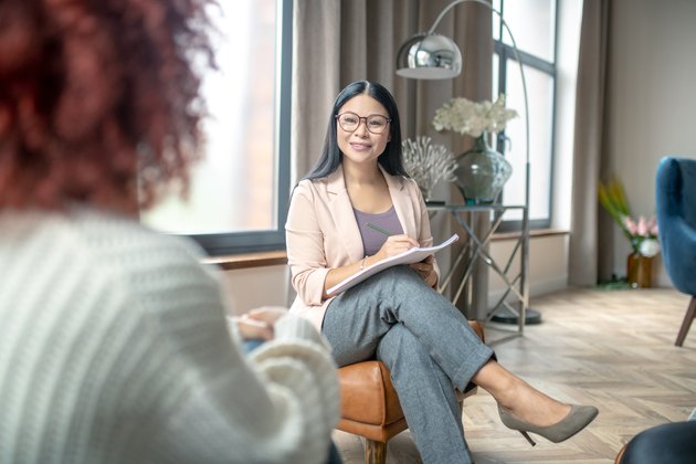 Pleasant psychologist wearing grey trousers smiling to client