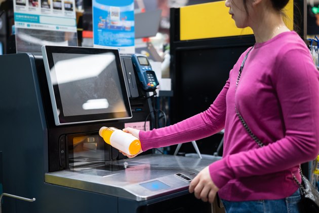 female checkout by automatic payment machine in supermarket