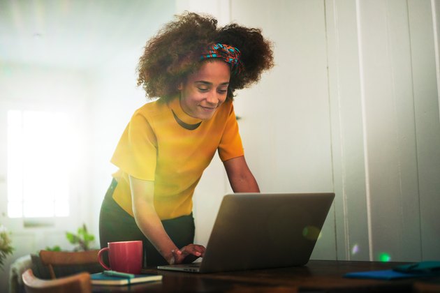 Woman stood using laptop at home