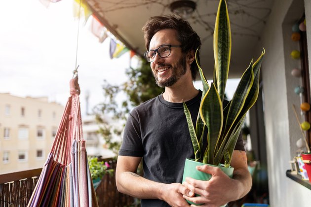 Young man taking care of his plants on a balcony