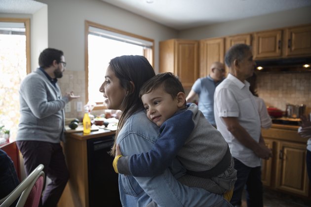 Latinx mother piggybacking toddler son in kitchen