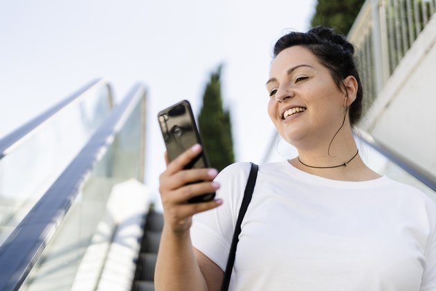 Smiling curvy young woman using mobile phone on escalator