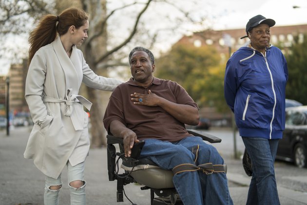 teenage girl talking and walking with a woman and a disabled man in wheelchair
