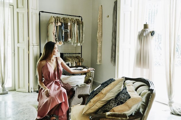 Woman sitting in boutique admiring dress on mannequin in window