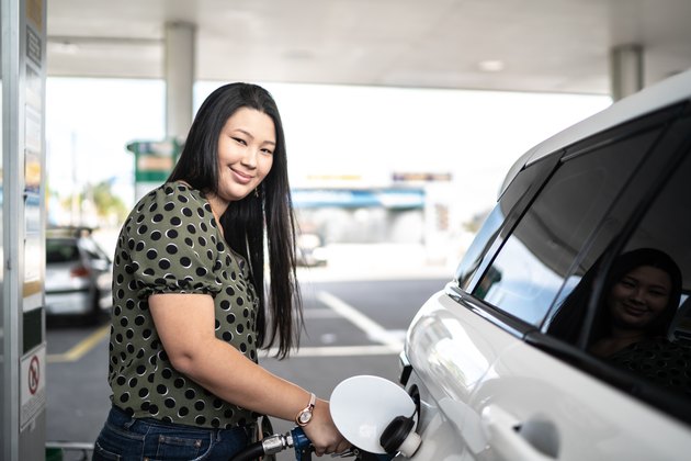 Portrait of young woman refueling her car at a gas station