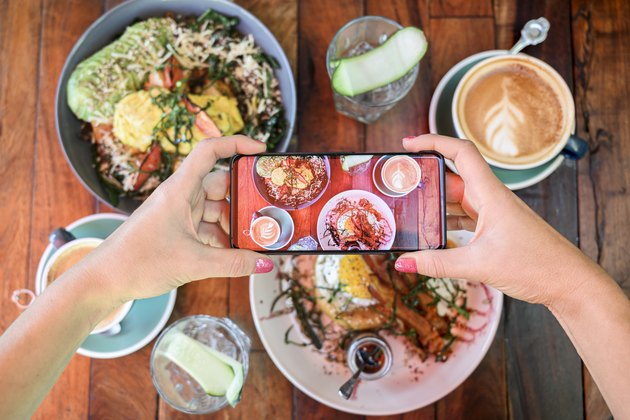 Woman photographing brunch meal in a cafe with smartphone, Mexico