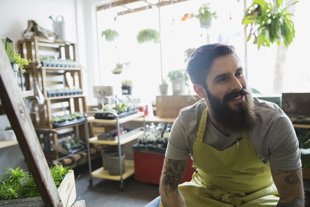 Smiling terrarium shop owner with beard looking away
