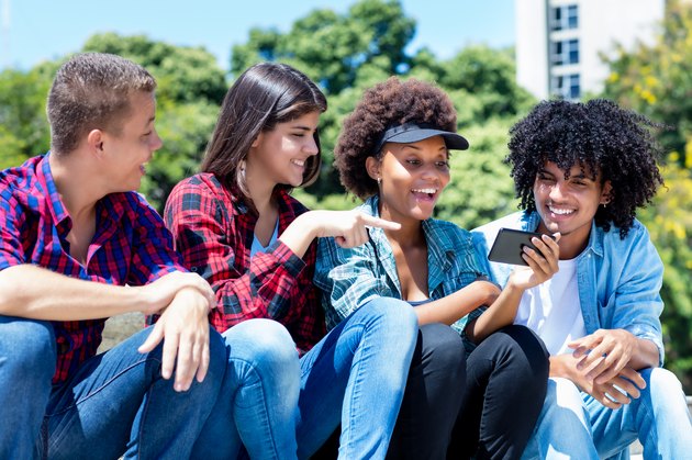 Laughing hispanic and african american hipster young adult people with phone