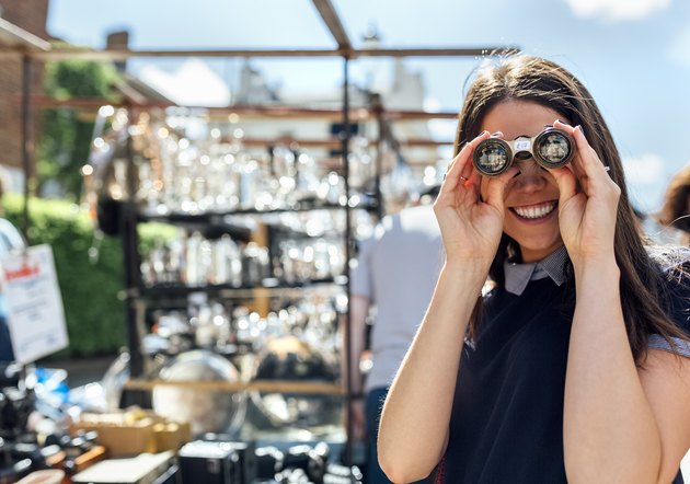 UK, London, Portobello Road, portrait of laughing woman looking through old binoculars
