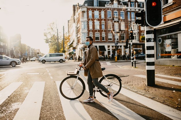 Man with face mask pushing bicycle in the city during coronavirus pandemic lockdown