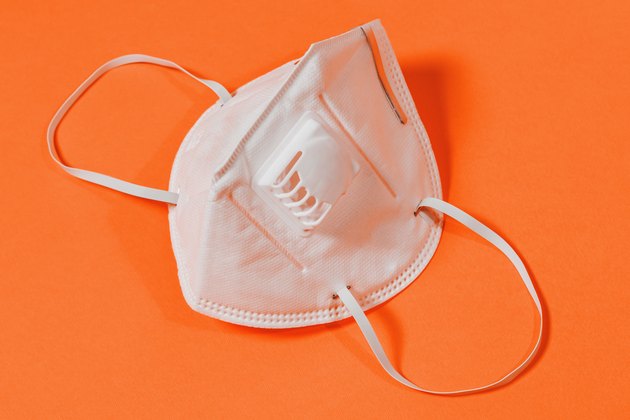 Medical mask with valve and surgical mask on orange background