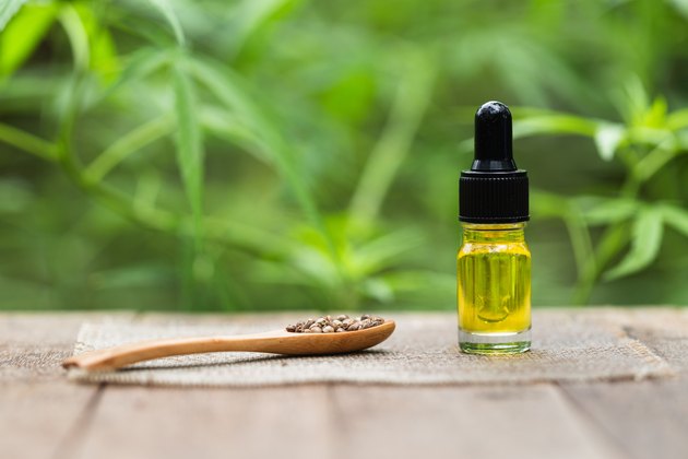 CBD Hemp oil, marijuana plant and cannabis oil on wooden table, medical marijuana oil concept
