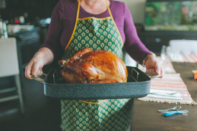 Midsection Of Woman Carrying Tray With Roast Turkey In Kitchen