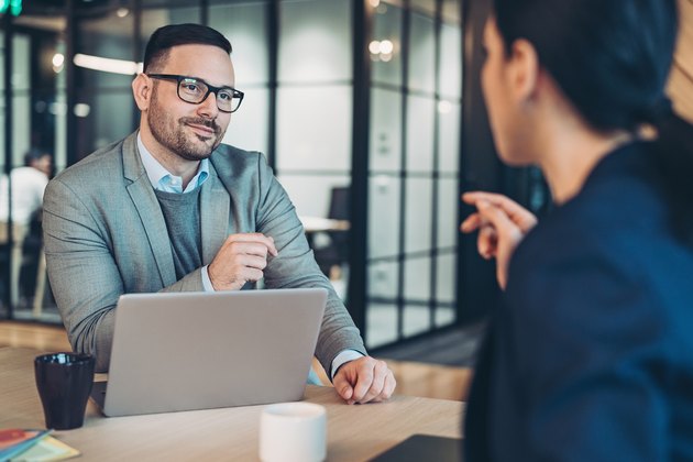 Couple of business persons sitting at a desk and talking