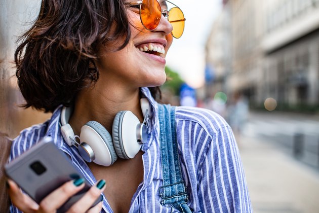 Portrait of modern young woman outdoors with smart phone