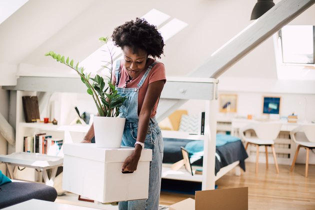 Young African-American woman carrying packed belongings while moving house