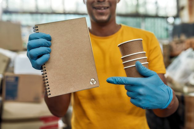 Notebook produced from recycled cups held by man