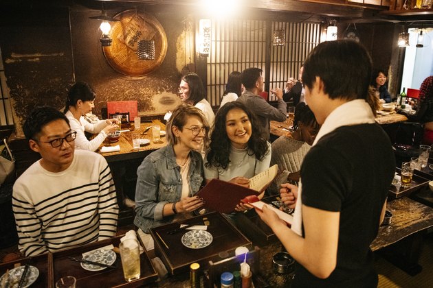Waiter taking food order from young women in Izakaya