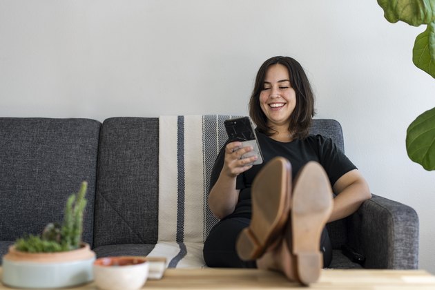 Woman sitting on couch with feet up on phone