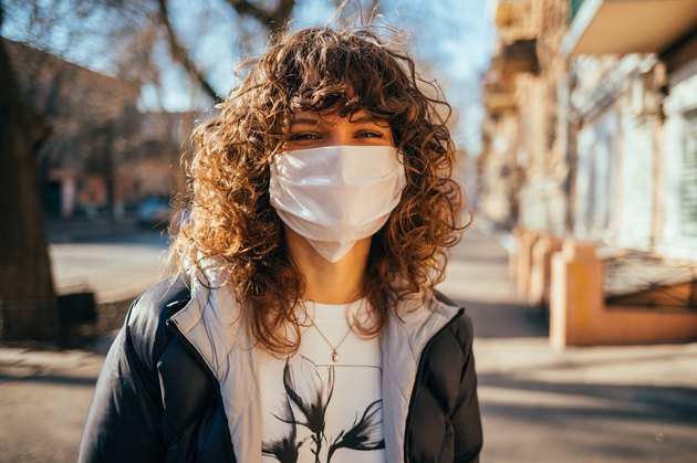 Happy young woman wearing facial mask for virus protection