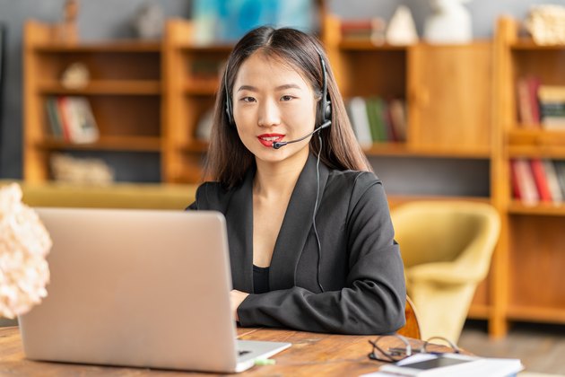 Smiling chinese support service agent consulting customer. Female portrait looking at camera
