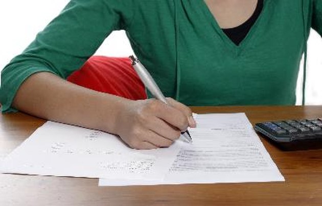 A young woman holding a pen, doing her taxes