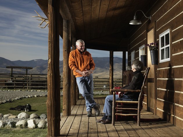 Senior man and woman having conversation on porch, smiling